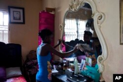 13-year-old Medege Dorlus cleans a mirror at the home she lives in, in Port-au-Prince, Haiti, May 27, 2017.
