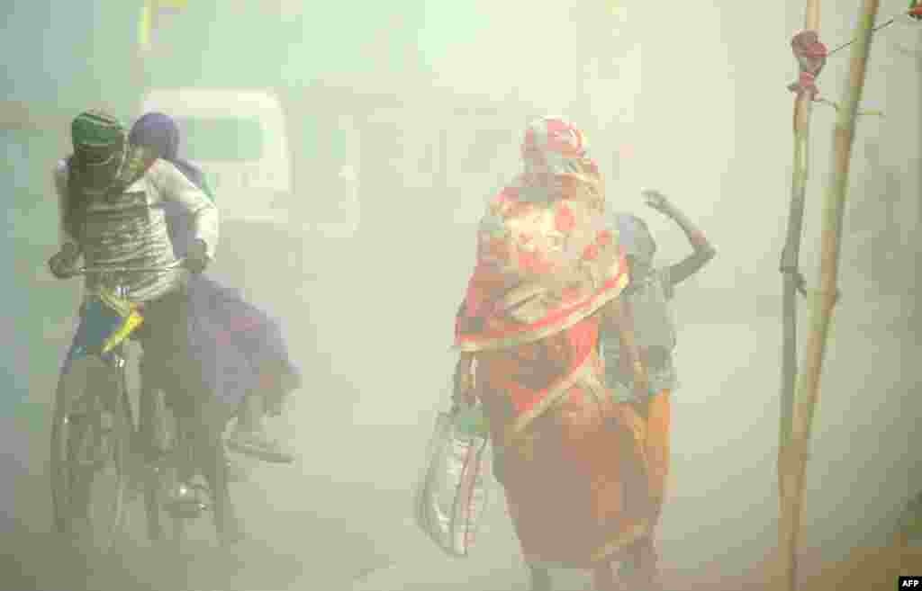 Pejalan kaki dan pesepeda melakukan perjalanan di tengah badai debu di Sangam, pertemuan sungai Gangga, Yamuna dan Saraswati yang mistis di Allahabad, India.