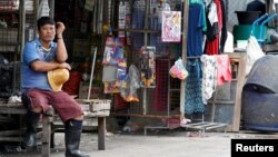 FILE - A Myanmar migrant worker rests outside his house near a wholesale market for shrimp and other seafood in Mahachai, in Samut Sakhon province, Thailand, July 4, 2017.