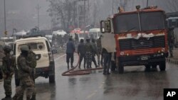 Indian firemen spray water on a road to wash away blood after an explosion in Pampore, Indian-controlled Kashmir, Feb. 14, 2019. 