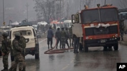 Indian firemen spray water on a road to wash away blood after an explosion in Pampore, Indian-controlled Kashmir, Feb. 14, 2019. 