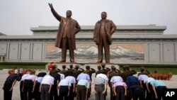 North Korean soldiers salute as others bow before the giant bronze statues of late North Korean leaders Kim Il Sung and his son Kim Jong Il during the anniversary of the end of World War II and liberation from Japanese colonial rule in Pyongyang, North Korea Wednesday, Aug. 15, 2018.