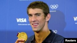 FILE - Michael Phelps poses with his gold medal for the 4x100m medley relay during a news conference with his sponsors at the London 2012 Olympic Games, August 5, 2012. 