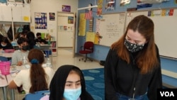 Substitute teacher Sophie Carter helps a student at McNair Upper Elementary School in Herndon, Fairfax County, Va. (Deborah Block/VOA)