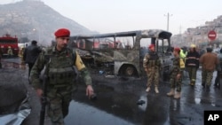 Afghan soldiers stand around a damaged bus at the site of a suicide attack by the Taliban in Kabul, Dec. 13, 2014. 