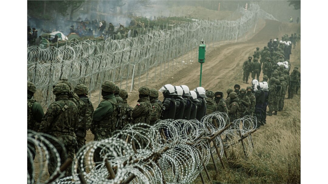 Tentara dan polisi Polandia mengawasi para migran di perbatasan Polandia/Belarus dekat Kuznica, Polandia, dalam foto yang dirilis oleh Pasukan Pertahanan Teritorial, 12 November 2021. (REUTERS)