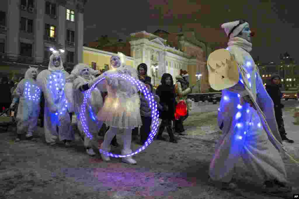 People dressed in illuminated angel costumes parade to mark Christmas Day in central Moscow, Russia, on Thursday, Dec. 25, 2014. (AP Photo/Pavel Golovkin)