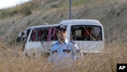 A police officer stands in front of the wreckage of a military bus after a roadside bomb blew up the bus in Istanbul, 22 Jun 2010