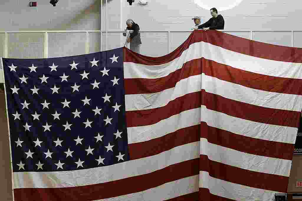 Trabajadores despliegan una gran bandera de Estados Unidos para un acto de Santorum, en Steubenville, Ohio.