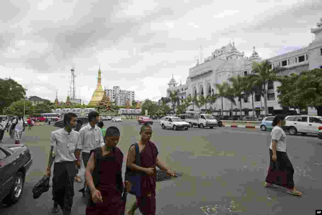 Para biarawan Buddha dan warga lain menyeberang jalan di Rangoon, Burma (13/5). Pemerintah Burma memperingatkan, Sabtu (11/5), bahwa angin topan baru akan menyerang pesisir barat minggu ini, yang menyebabkan kekhawatiran akan nasib puluhan ribu pengungsi Rohingya Muslim. (AP/Khin Maung Win)