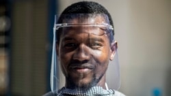 In this photo taken Thursday, April 16, 2020, Idrissa Sall demonstrates a protective face shield made with a laser cutter, to be used to protect against transmission of the coronavirus, at the FabLab workshop at the Ker Thiossane multimedia center. (AP Photo/Sylvain Cherkaoui)