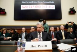 The national debt is shown behind Federal Reserve Chairman Jerome Powell as arrives to testify on the semiannual monetary policy report to the House Financial Services Committee, Tuesday, Feb. 27, 2018, in Washington.