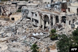 A picture taken on July 3, 2016 from the UNESCO-listed citadel shows the partially collapsed building of the famed Carlton Citadel Hotel (L), in the government-controlled side of the divided northern Syrian city of Aleppo.