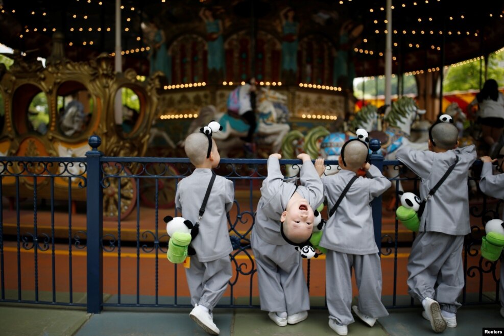 Boys, who are experiencing the lives of Buddhist monks by staying in a temple for two weeks as novice monks, look at a carousel at the Everland amusement park in Yongin, South Korea.