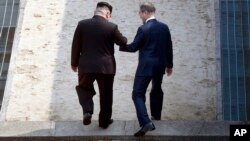 27일 판문점에서 만난 김정은 북한 국무위원장과 문재인 한국 대통령이 경계석 넘어 북측 지역에 들어가고 있다.