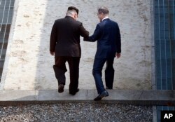 Pemimpin Korea Utara Kim Jong-un (kiri) dan Presiden Korea Selatan Moon Jae-in melintasi garis demarkasi militer di desa perbatasan Panmunjom di Zona Demiliterisasi, Jumat, 27 April 2018. (Foto: dok).