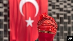 A masked protester is backdropped by a Turkish flag on the edge of Gezi Park, in Istanbul, Turkey, June 12, 2013.