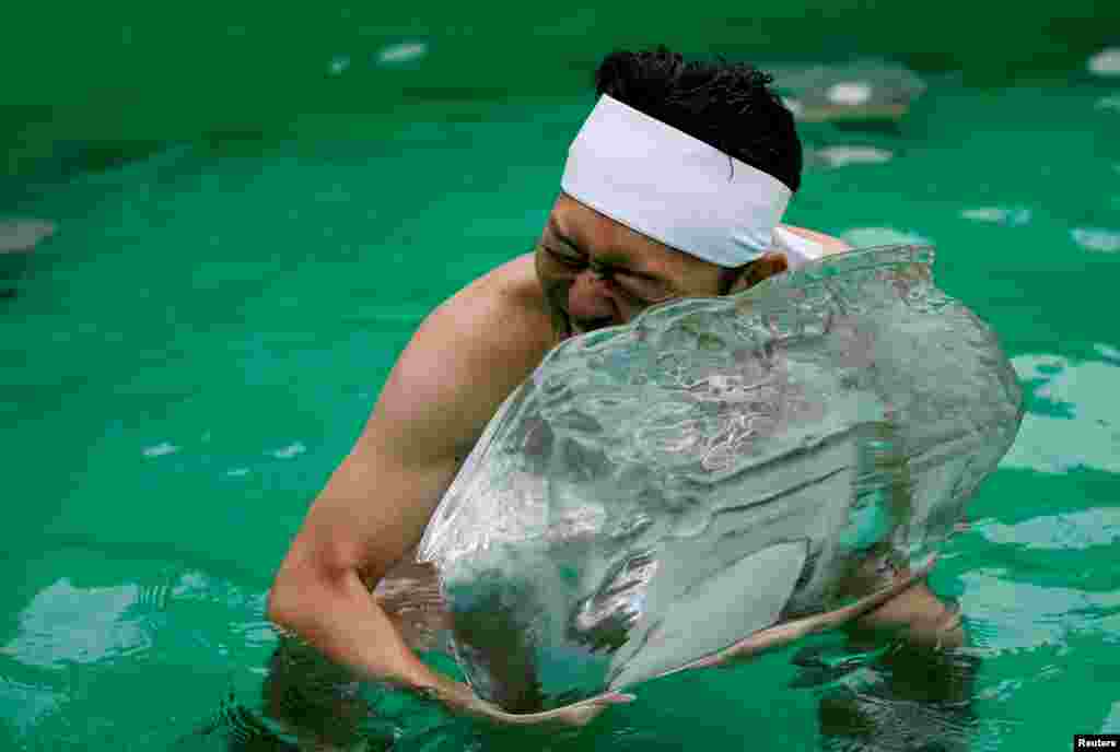 A man holds an ice brick after praying in a ceremony to purify his soul and wish for good health in the New Year at the Teppozu Inari shrine in Tokyo, Japan.