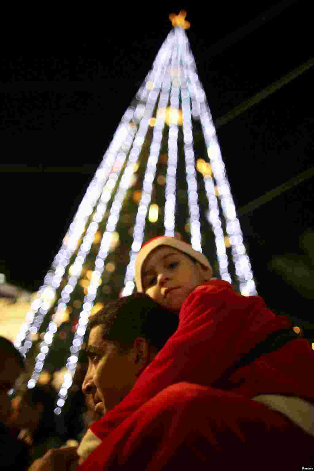 A boy wearing a Santa Claus costume is carried by his father during a Christmas tree lighting ceremony in the northern town of Nazareth, the town of Jesus' boyhood, December 12. 