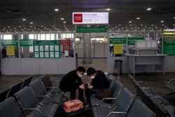 Passengers check their smartphones as they wait in an empty hall inside Sheremetyevo international airport outside Moscow, March 18, 2020. Russian authorities are taking strong steps to try to prevent the spread of coronavirus.