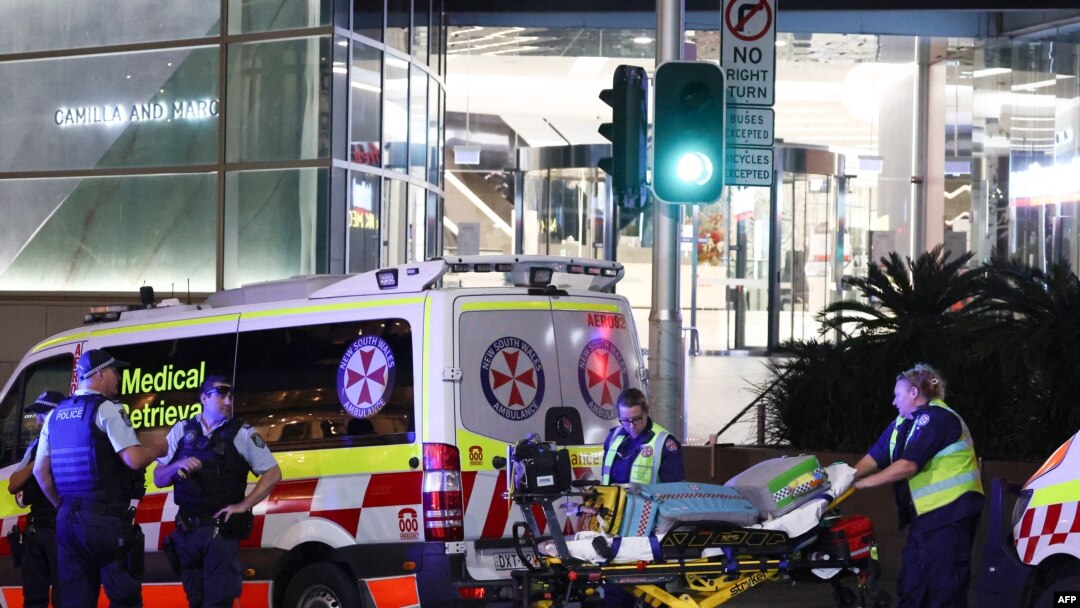 Paramedics (R) move a stretcher with medical equipment outside the Westfield Bondi Junction shopping mall after a stabbing incident in Sydney on April 13, 2024.