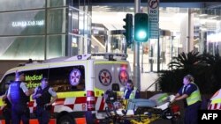 Paramedics (R) move a stretcher with medical equipment outside the Westfield Bondi Junction shopping mall after a stabbing incident in Sydney on April 13, 2024.