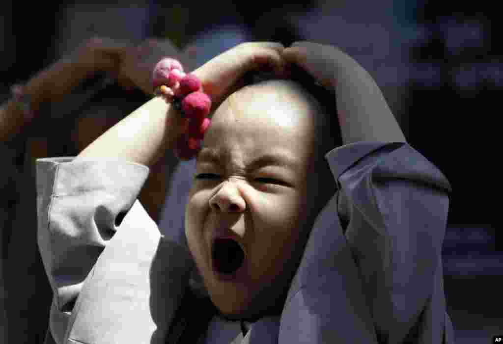 A shaven-headed young boy, who was among ten children who entered a temple to have an experience of monks&#39; life for three weeks, yawns while attending a volunteer activity in Seoul, South Korea.