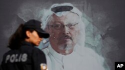 FILE - A Turkish police officer walks past a picture of slain Saudi journalist Jamal Khashoggi prior to a ceremony, near the Saudi Arabia consulate in Istanbul, marking the one-year anniversary of his death, Oct. 2, 2019.