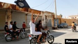 A resident of Tabqa city touring the streets on a motorcycle waves an Islamist flag in celebration after Islamic State militants took over Tabqa air base, in nearby Raqqa, Syria, Aug. 24, 2014. 