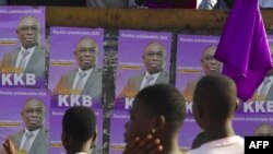 Men stand in front of posters of Ivory Coast's presidential candidate Bertin Kouadio Konan in the Koumassi disctrict in Abidjan on the last day of the country's presidential campaign on Oct. 29, 2020.