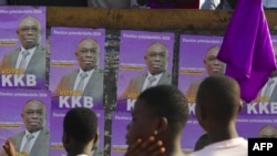 Men stand in front of posters of Ivory Coast's presidential candidate Bertin Kouadio Konan in the Koumassi disctrict in Abidjan on the last day of the country's presidential campaign on Oct. 29, 2020.