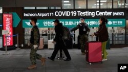 Para pelancong dari China berjalan melalui pusat pengujian COVID di bandara Incheon, Seoul, Korea Selatan, Selasa (10/1). Beberapa negara telah memberlakukan persyaratan pengujian COVID-19 pada para pendatang dari China.