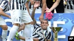 Juventus' Carlos Tevez, of Argentina, celebrates next to the Serie A trophy following the match between Juventus and Cagliari, Turin, Italy, May 18, 2014.