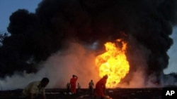 FILE - Firefighters try to extinguish a fire at a damaged oil well of the state owned Oil India Ltd. at Dikom, in the northeastern Indian state of Assam.