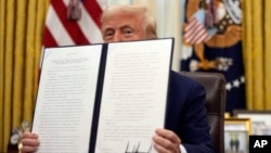 El presidente Donald Trump sostiene una orden ejecutiva firmada sobre la desclasificación y publicación de los registros relacionados con los asesinatos de los hermanos Kennedy y el reverendo Martin Luther King, Jr., la Casa Blanca, el jueves 23 de enero de 2025, en Washington. 