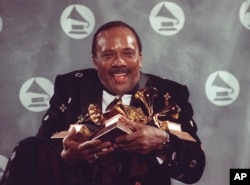 FILE - Quincy Jones cradles his Grammy awards including the album of the year award, for his eclectic album "Back on the Block" during the 33rd annual Grammy Awards, on Feb. 20, 1991. (AP Photo/Susan Ragan, File)