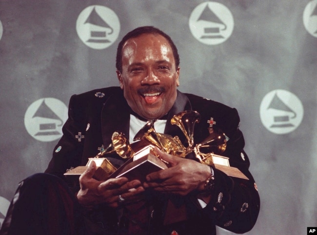 FILE - Quincy Jones cradles his Grammy awards including the album of the year award, for his eclectic album "Back on the Block" during the 33rd annual Grammy Awards, on Feb. 20, 1991. (AP Photo/Susan Ragan, File)