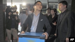 A policeman carries a box containing confiscated goods at Google Inc's office in Seoul May 3, 2011.