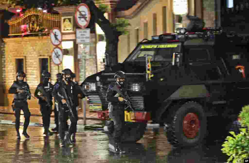 Police officers walk past an armored vehicle at the National Police Headquarters following a suspected militant attack in Jakarta, Indonesia.