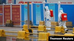 Workers in PPE spray the ground with diinfectant in Baishazhou market during a visit of World Health Organization (WHO) team tasked with investigating the origins of the coronavirus (COVID-19) pandemic, in Wuhan