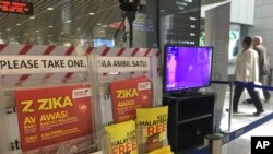 People walk past a travel advisory on the Zika virus infection in Kuala Lumpur International Airport in Sepang, Malaysia, Aug. 28, 2016. 