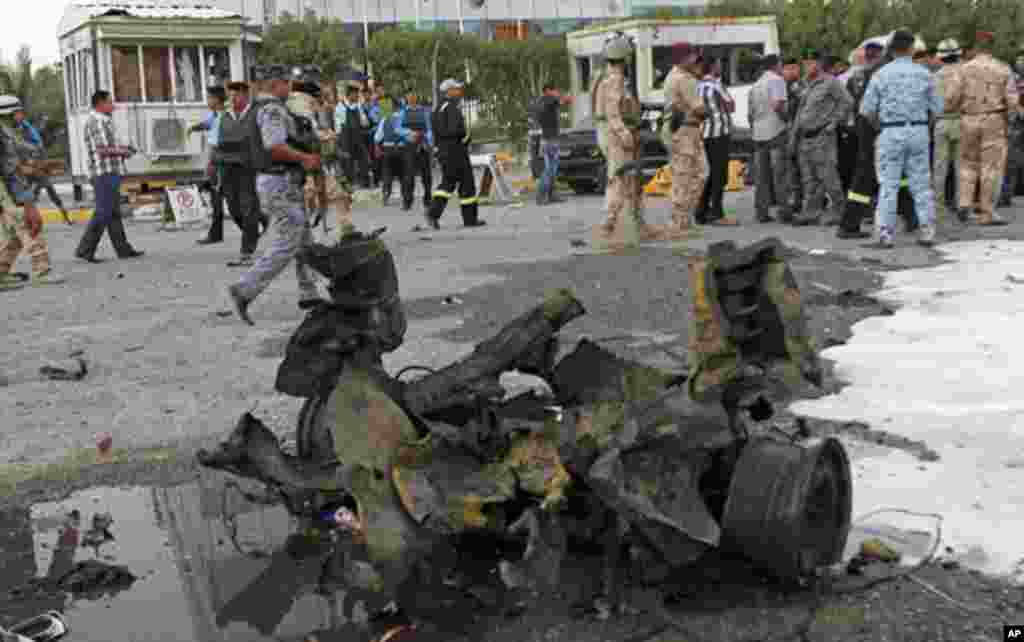 People and security forces inspect the scene of a car bomb attack in Basra, 340 miles (550 kilometers) southeast of Baghdad, Iraq, July 2, 2013. 