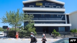FILE - People walk past the Nalia Radio and Television (NRT) building in Sulaimaniyah city, in the Kurdish autonomous region of northern Iraq, Aug. 22, 2020.