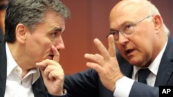 French Finance Minister Michel Sapin talk to Greek Finance Minister Euclid Tsakalotos, left, during a meeting of eurozone finance ministers at the EU Council building in Brussels, Aug. 14, 2015. 