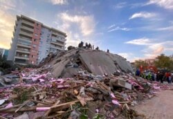 Rescue workers try to save people trapped in the debris of a collapsed building, in Izmir, Turkey, Oct. 30, 2020. A strong earthquake struck Friday in the Aegean Sea between the Turkish coast and the Greek island of Samos.