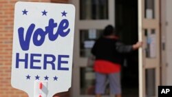 FILE - An election worker enters a polling station in Charlotte, N.C., April 24, 2019, as the station prepares for early voting.