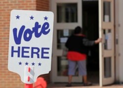 FILE - An election worker enters a polling station in Charlotte, North Carolina, April 24, 2019, as the station prepares for early voting.