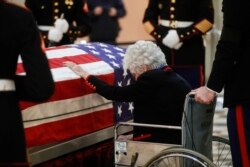 FILE - Annie Glenn touches the casket of her husband, John Glenn, as he lies in repose at the Ohio Statehouse in Columbus, Dec. 16, 2016.
