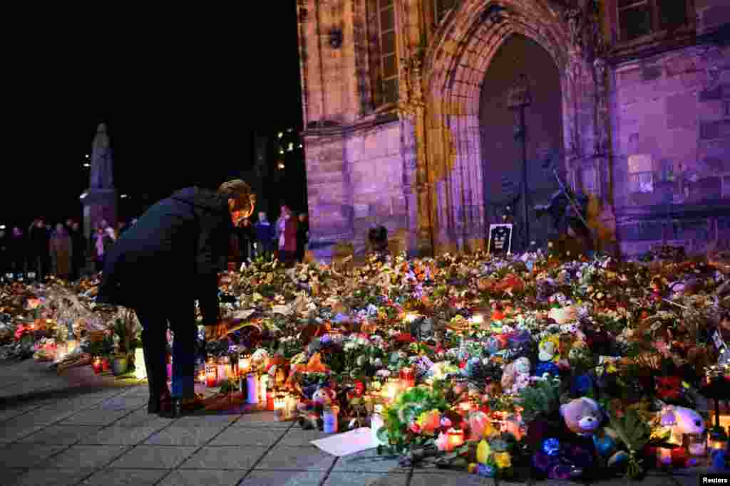 A woman places a tribute with flowers and candles left near the &#39;Alter Markt&#39; Christmas market, where a man drove a car into the crowd through an emergency exit route on Dec. 20, in Magdeburg, Germany.