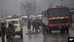 Seorang petugas pemadam kebakaran India menyemprotkan air di jalan untuk membersihkan bekas darah setelah ledakan di Pampore, Kashmir yang dikuasai India, 14 Februari 2019.